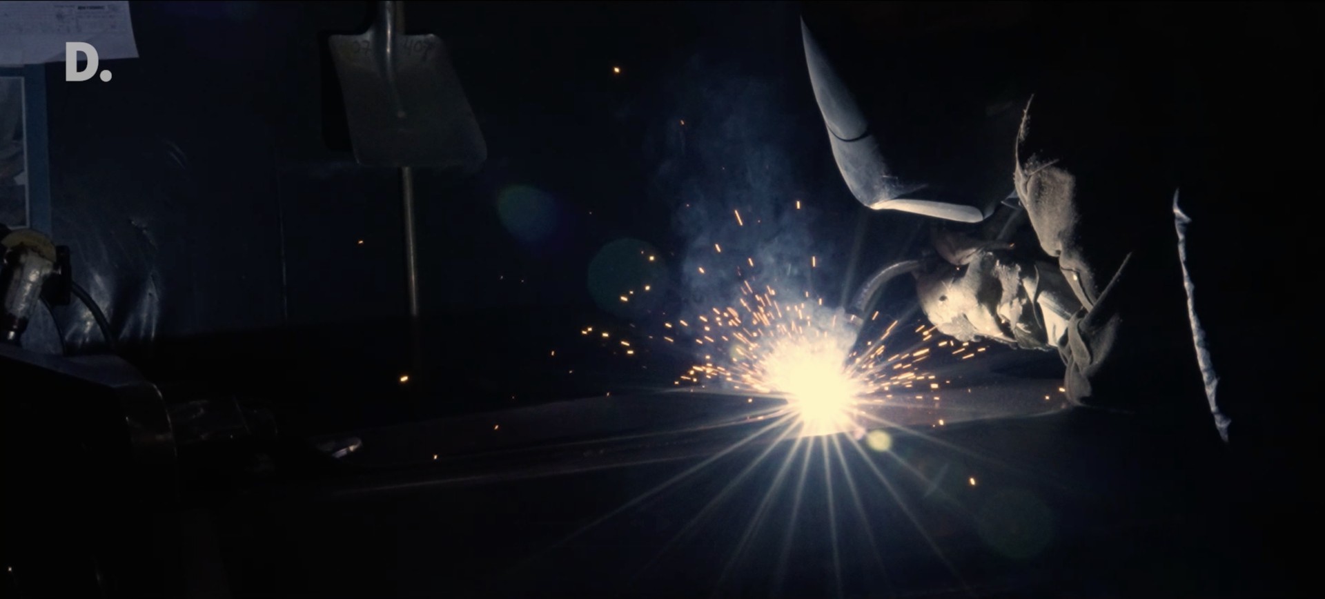 A welder at work in the Rotobec factory, lit by a burst of sparks